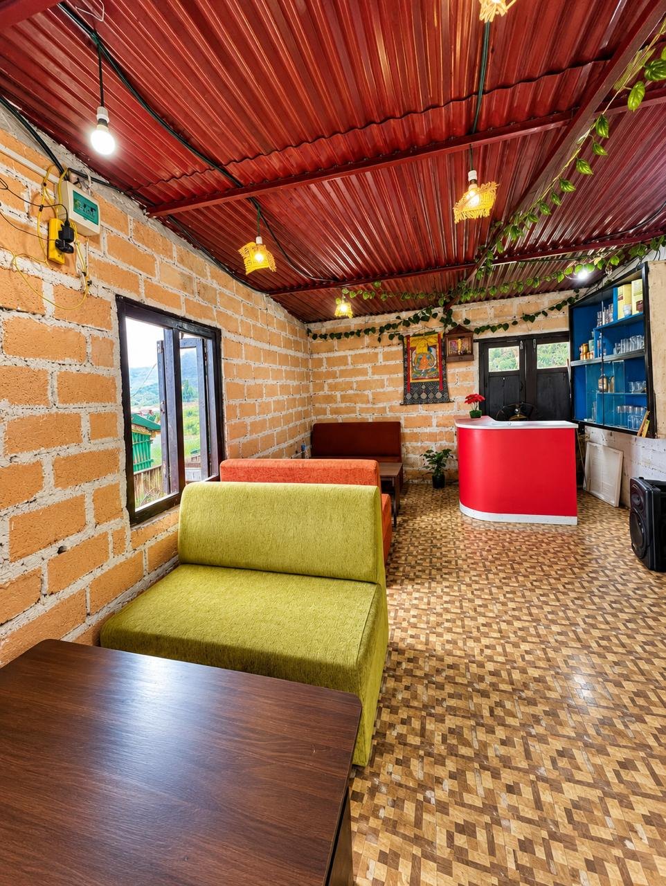 Brick room with green and orange sofas and a red bar counter