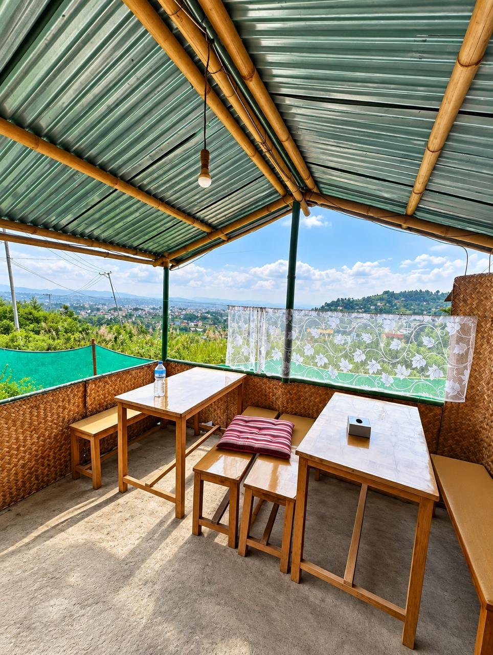 Wooden tables under the bamboo roof on the terrace, looking out over the valley